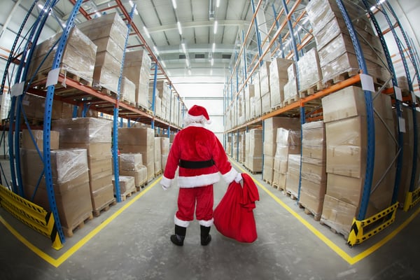 red-santa-in-suit-with-sack-standing-distribution-center-parcels-in-aisles